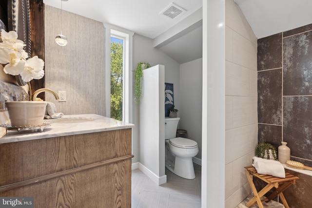 bathroom with vanity, toilet, baseboards, vaulted ceiling, and visible vents