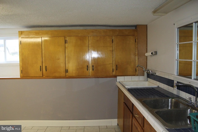 577 Winchester St, Paw Paw, WV 25434 - kitchen with a sink, baseboards, a textured ceiling, decorative backsplash, and brown cabinetry