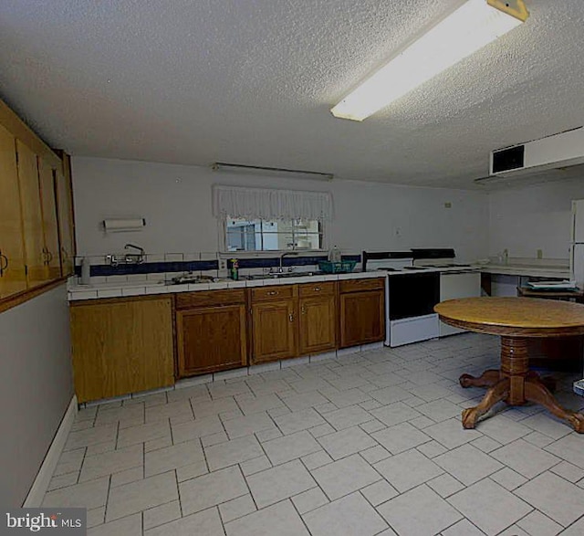 577 Winchester St, Paw Paw, WV 25434 - kitchen featuring a textured ceiling, tile countertops, brown cabinets, a sink, and electric range
