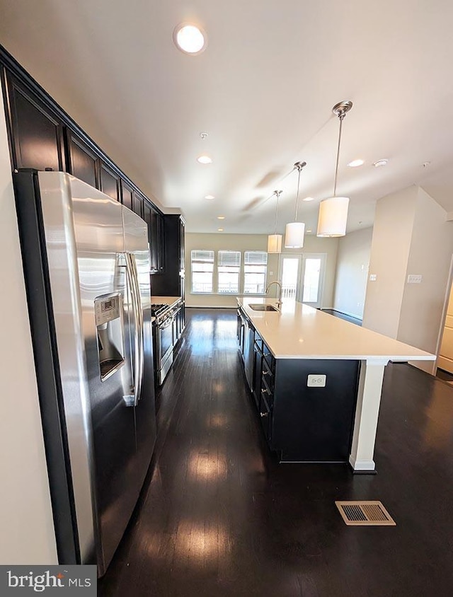 kitchen featuring visible vents, dark wood-type flooring, light countertops, a sink, and appliances with stainless steel finishes