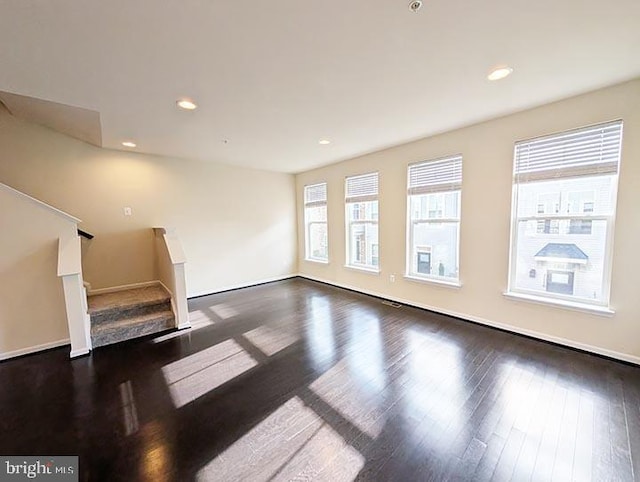 unfurnished living room featuring stairs, recessed lighting, baseboards, and wood finished floors