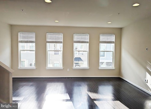 empty room featuring recessed lighting, baseboards, and wood finished floors