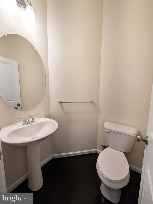 bathroom with toilet, baseboards, and wood finished floors