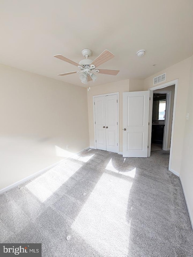 unfurnished bedroom featuring visible vents, carpet floors, a closet, baseboards, and a ceiling fan