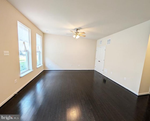 unfurnished room featuring ceiling fan, visible vents, dark wood-style floors, and baseboards