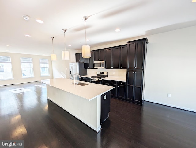 kitchen featuring a sink, stainless steel appliances, dark wood-style flooring, and an island with sink