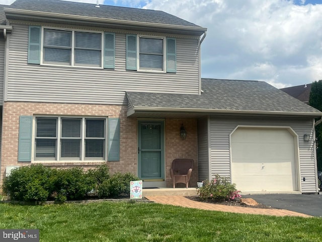 view of front of home with an attached garage, brick siding, asphalt driveway, a front lawn, and roof with shingles