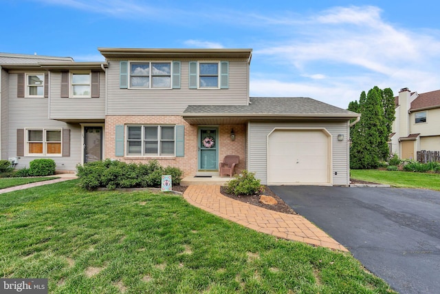 townhome / multi-family property with an attached garage, driveway, a front lawn, and brick siding