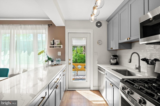1705 N Cliff St, Alexandria, VA 22301 - kitchen featuring appliances with stainless steel finishes, gray cabinets, a sink, tasteful backsplash, and light stone countertops
