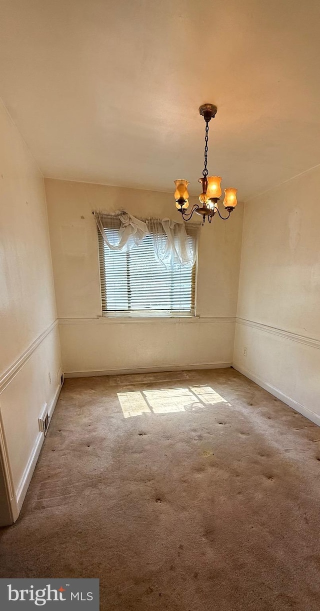 carpeted spare room with a chandelier