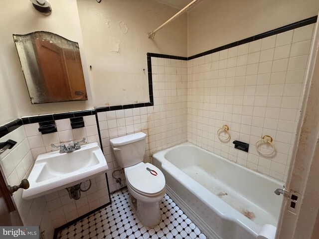 bathroom with wainscoting, a sink, toilet, tile walls, and shower / bathing tub combination