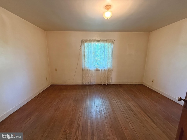 empty room with wood-type flooring and baseboards
