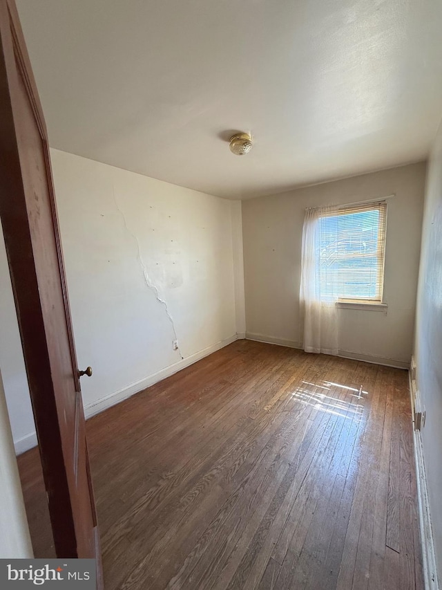 spare room featuring baseboards and hardwood / wood-style floors