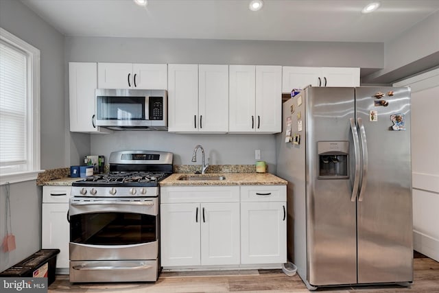 825 Wicklow Rd, Baltimore, MD 21229 - kitchen with stainless steel appliances, a sink, light wood-type flooring, white cabinets, and light stone counters
