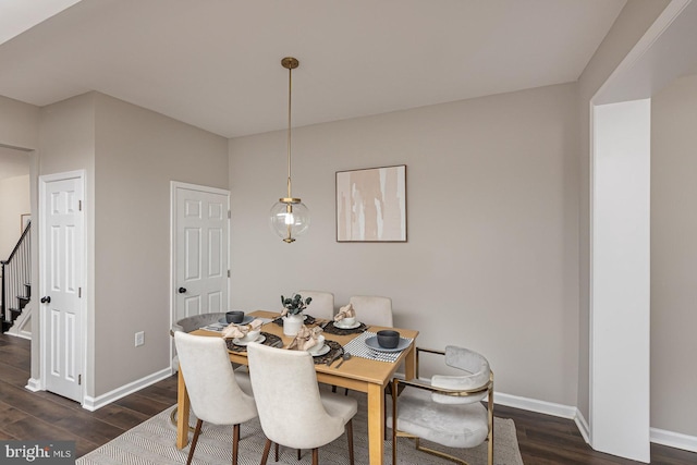 dining room featuring baseboards, dark wood-style floors, and stairs
