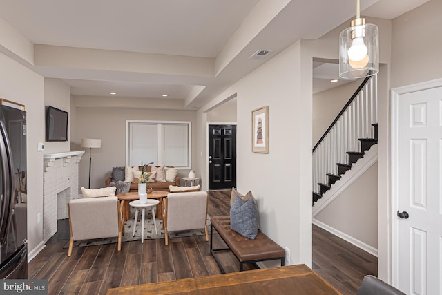 living area with stairs, baseboards, dark wood finished floors, and a fireplace