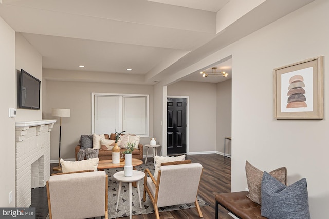 living area featuring dark wood-style flooring, a brick fireplace, baseboards, a chandelier, and recessed lighting