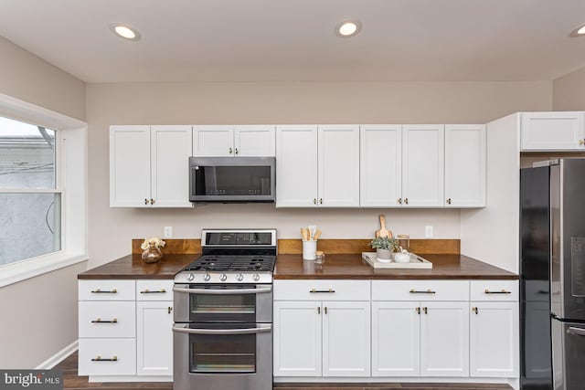 kitchen featuring recessed lighting, baseboards, white cabinets, and stainless steel appliances