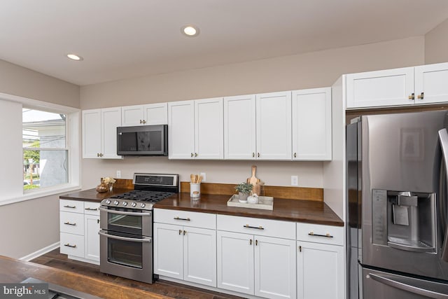 kitchen with white cabinets, butcher block countertops, and appliances with stainless steel finishes
