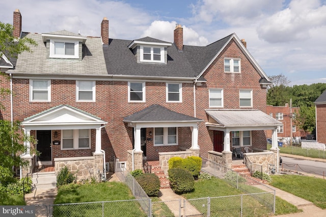 multi unit property with covered porch, brick siding, a chimney, and a fenced front yard