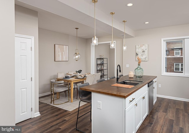 kitchen with stainless steel dishwasher, a sink, wood counters, and dark wood finished floors