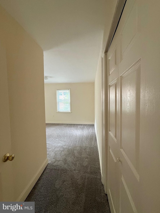 corridor with baseboards and carpet flooring