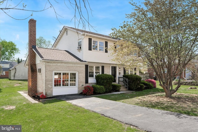 colonial home featuring brick siding, a chimney, a front yard, and roof with shingles