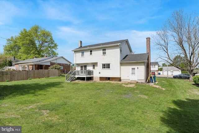 rear view of house with a lawn, fence, a chimney, and a deck