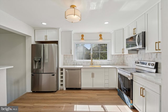 kitchen featuring decorative backsplash, light countertops, white cabinetry, a sink, and stainless steel appliances