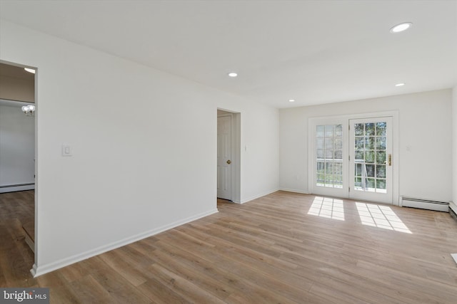 spare room featuring baseboard heating, recessed lighting, and wood finished floors