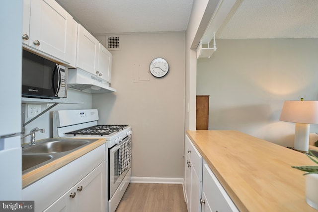 kitchen featuring visible vents, white appliances, a textured ceiling, under cabinet range hood, and light wood finished floors