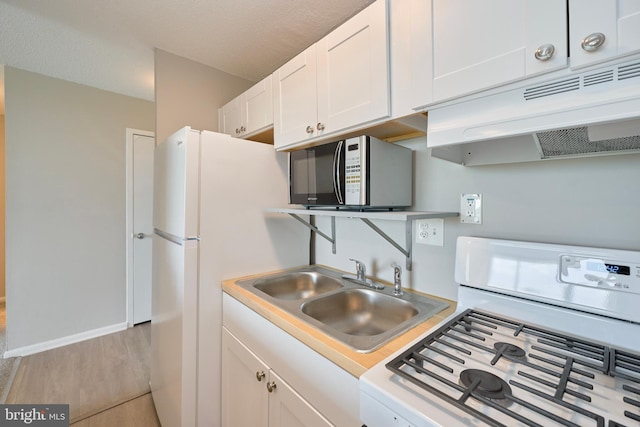kitchen featuring white appliances, light countertops, white cabinetry, under cabinet range hood, and a sink