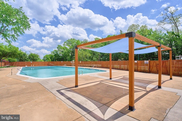 community pool with a patio area and fence