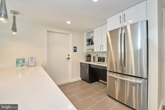 kitchen featuring dark tile patterned floors, a sink, light countertops, white cabinets, and freestanding refrigerator