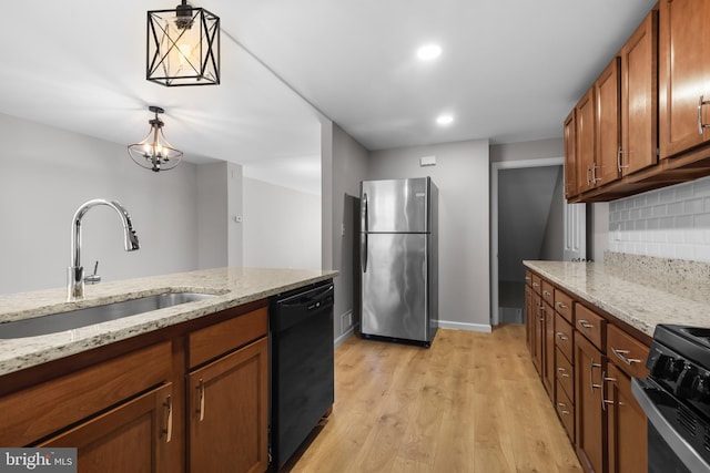 kitchen featuring a sink, brown cabinetry, light wood-type flooring, black appliances, and backsplash