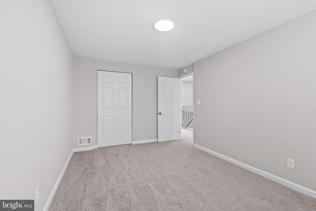 unfurnished bedroom featuring baseboards, carpet flooring, a closet, and visible vents