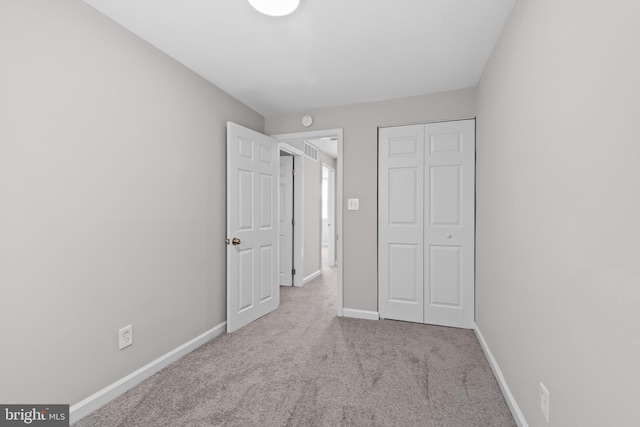 unfurnished bedroom featuring baseboards, a closet, visible vents, and carpet floors