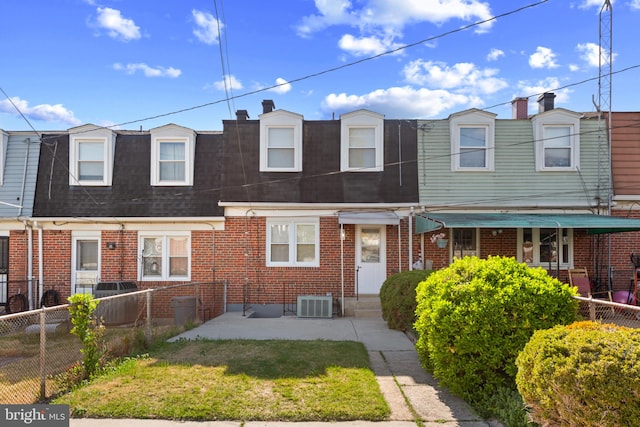 view of front of home with brick siding, roof with shingles, fence, and central AC
