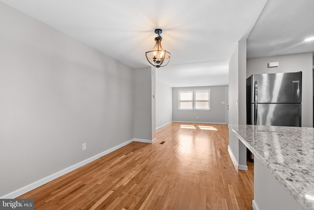 interior space with light wood finished floors, baseboards, and a notable chandelier