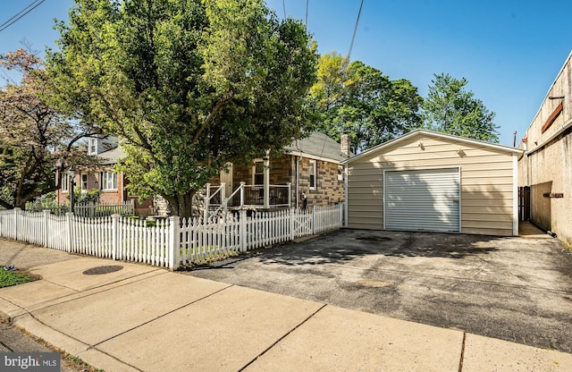 1016 Leiper St, Crum Lynne, PA 19022 - view of front of house with covered porch, a fenced front yard, an outbuilding, a detached garage, and concrete driveway