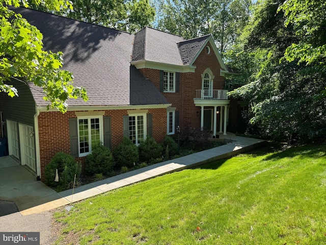 view of front of property with brick siding, a balcony, a front yard, a shingled roof, and an attached garage