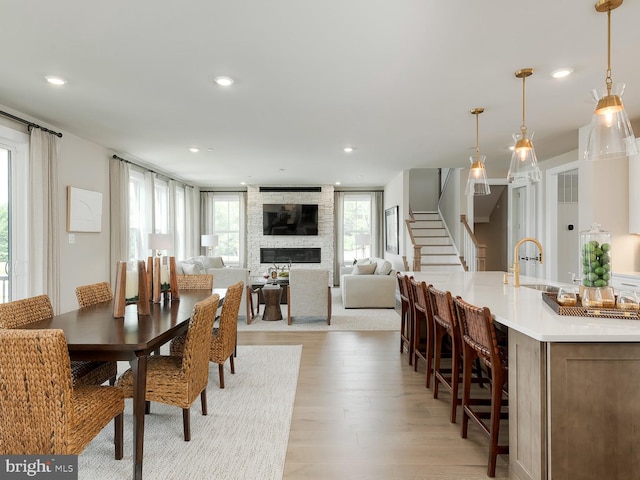 dining area featuring light wood-style floors, stairway, a fireplace, and recessed lighting