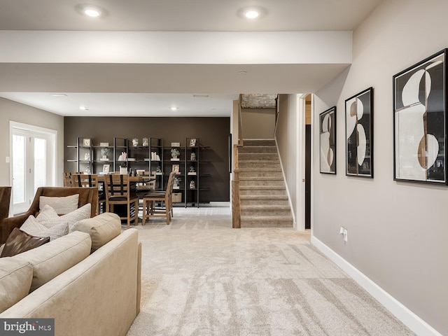 living room featuring baseboards, carpet, and stairs
