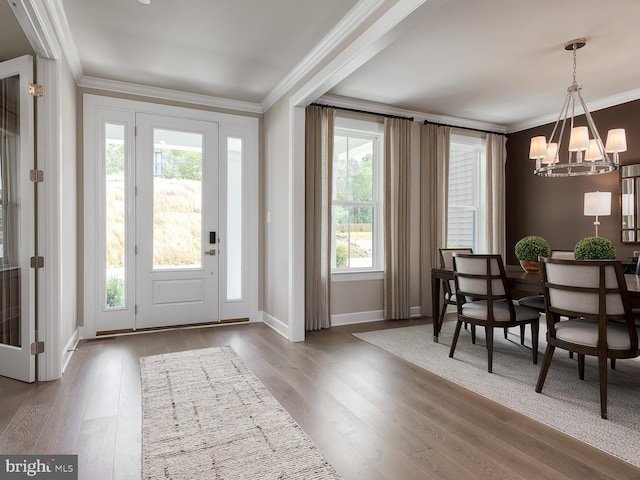 entryway with crown molding, baseboards, an inviting chandelier, and wood finished floors