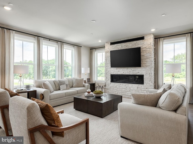 living area featuring recessed lighting and a stone fireplace