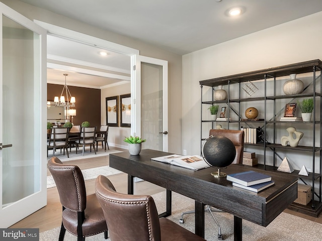 office space featuring crown molding, baseboards, wood finished floors, and a chandelier