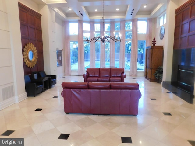 living area featuring visible vents, crown molding, a towering ceiling, a chandelier, and coffered ceiling