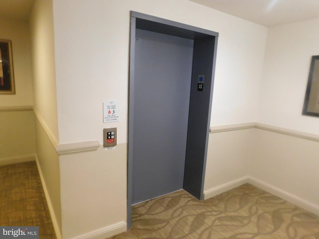 corridor with baseboards, carpet, and elevator