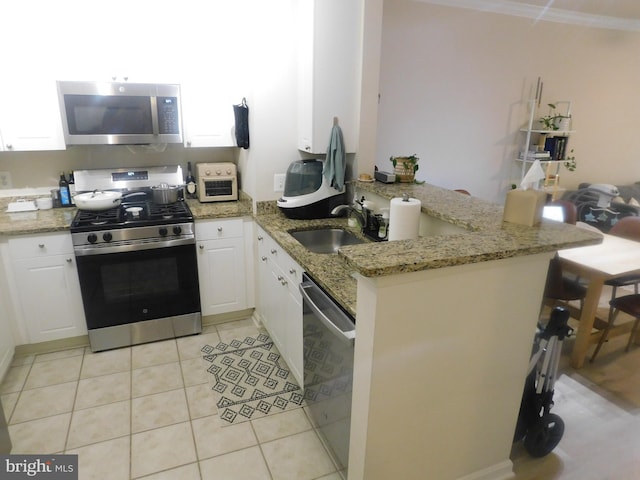 kitchen featuring light stone counters, stainless steel appliances, a peninsula, and white cabinetry