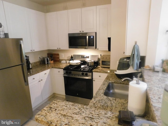 kitchen with appliances with stainless steel finishes, light stone countertops, and white cabinetry